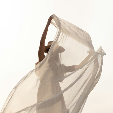 Woman lifting a piece of light fabric